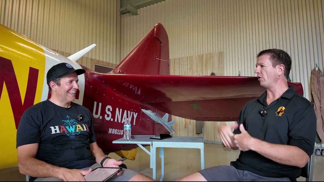 @CaptainMike350 and Patrick &ldquo;ManBear&rdquo; Williams talking in a hangar beside a red and yellow US Navy trainer aircraft